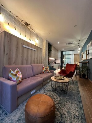 A modern living room with a sofa, ottoman, and red chair. - Magnificent brand-new home next to Plaza España (Valencia)