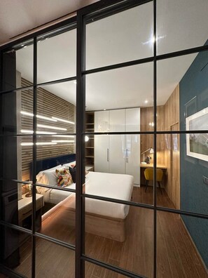 A modern hotel room with a large bed, a desk, and a wardrobe. - Magnificent brand-new home next to Plaza España (Valencia)