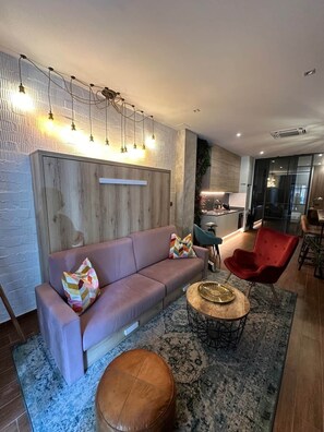A modern living room with a sofa, ottoman, and red chair, a coffee table, and a patterned rug. - Magnificent brand-new home next to Plaza España (Valencia)