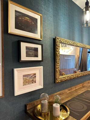 A wall with framed pictures, a mirror with an ornate frame, and a tray with candles. - Magnificent brand-new home next to Plaza España (Valencia)