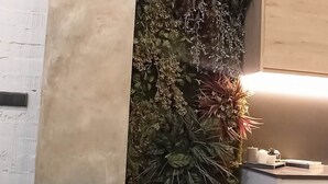 A room with a teal chair, a small table with books, a wall-mounted plant, and a cabinet. - Magnificent brand-new home next to Plaza España (Valencia)