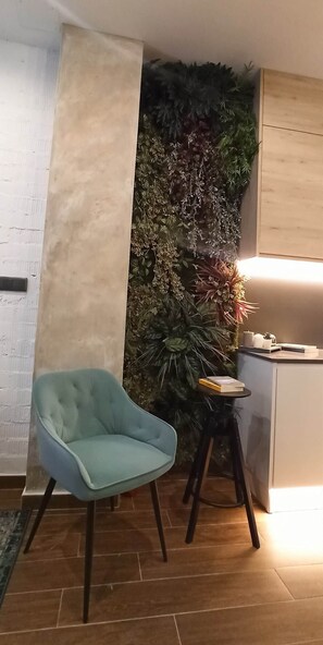A room with a teal chair, a small table with books, a wall-mounted plant, and a cabinet. - Magnificent brand-new home next to Plaza España (Valencia)
