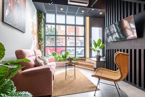 A modern living room with a sofa, a wicker chair, a small table, and a large window with a view of the street. - To complete (Valencia)