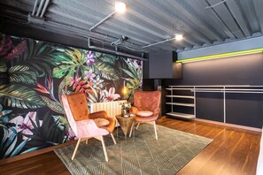 A modern interior with a tropical-themed wall mural, a wooden floor, and a seating area with two chairs and a small table. - To complete (Valencia)