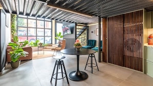 A modern interior with a round table, bar stools, a sofa, and a large window. - To complete (Valencia)