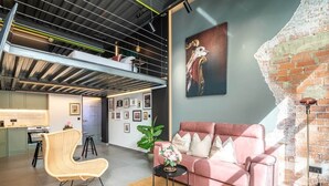 A modern living space with a loft area, a pink sofa, a wicker chair, and a large artwork on the wall. - To complete (Valencia)