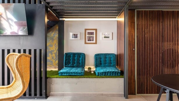 A modern interior with a seating area featuring two teal chairs, a wicker chair, and a table. - To complete (Valencia)