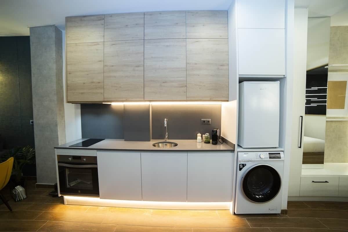 Een moderne keuken met inbouwapparatuur, een spoelbak en een wasmachine.