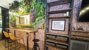 A bar area with a mirror, stools, and a brick wall with greenery. - Fabulous new home just a stone's throw from Plaza España (Valencia)