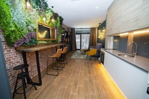 A modern kitchen with a bar area, a large mirror, and a green wall with plants. - Fabulous new home just a stone's throw from Plaza España (Valencia)