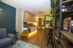 Eine moderne Küche mit einer zentralen Kochinsel, einem Essbereich mit Barhocker und einer Sitzecke mit Sofa und Sesseln.