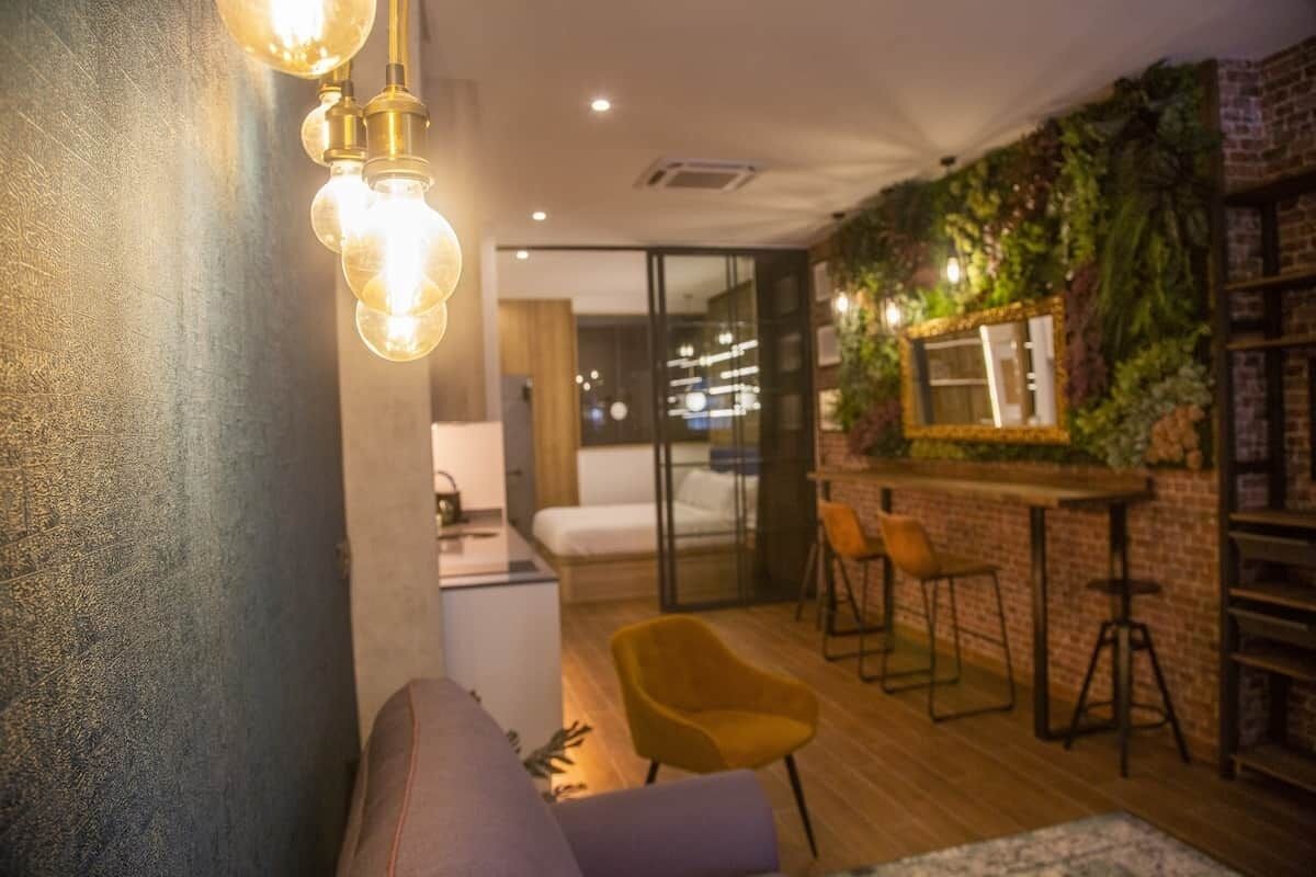 Un intérieur moderne comprenant un canapé, un coin repas avec des tabourets de bar et un espace cuisine.