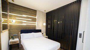 A modern bedroom with a bed, bedside tables, a wall-mounted light fixture, and a sliding door. - Fabulous new home just a stone's throw from Plaza España (Valencia)