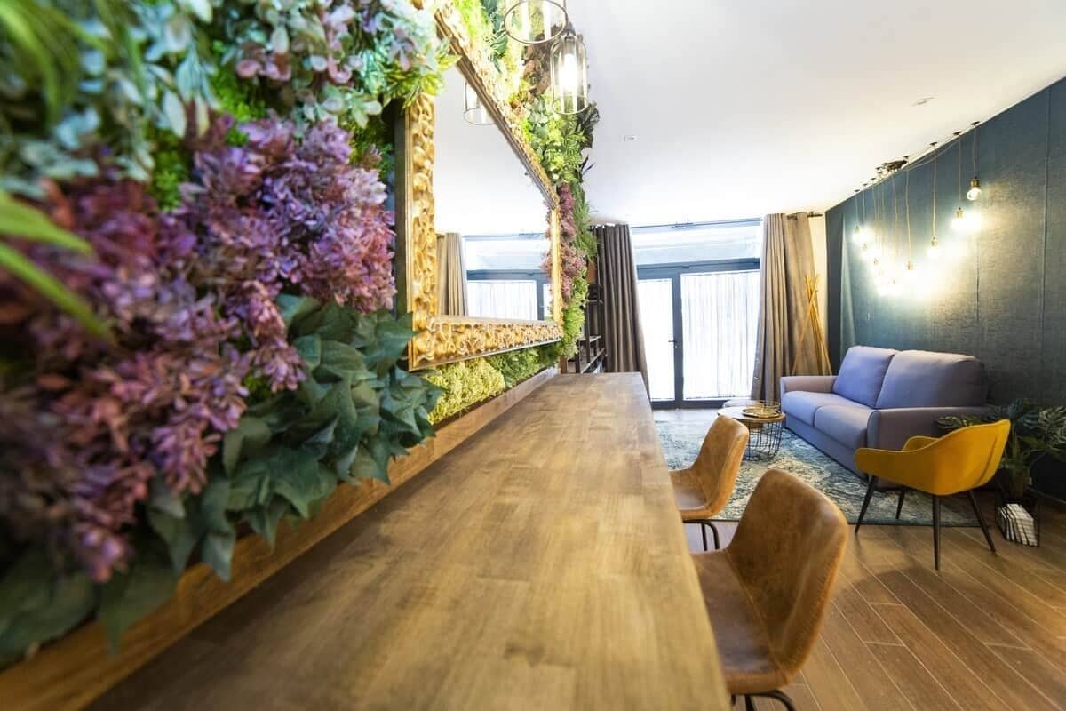 Een moderne woonkamer met een houten eettafel, een bank en een grote spiegel.