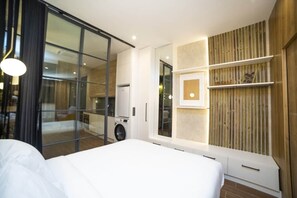 A modern bedroom with a large bed, a sliding glass door leading to a bathroom, and a built-in wardrobe with shelves. - Fabulous new home just a stone's throw from Plaza España (Valencia)
