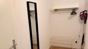 Een hal met een deur, een spiegel, een bankje, een haardroger en een radiator.