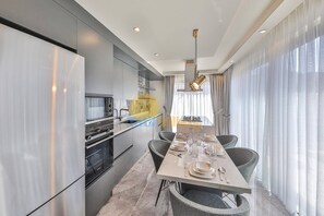 A modern kitchen with built-in appliances and a dining area with a table set for four. - Luxury Villa Petra w Ndoor Heated Pool, Sauna (Kaş)