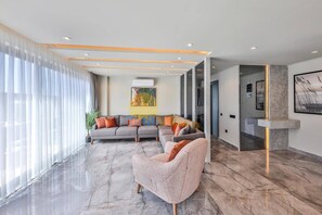 A modern living room with a sectional sofa, a patterned armchair, and a large window with sheer curtains. - Luxury Villa Petra w Ndoor Heated Pool, Sauna (Kaş)
