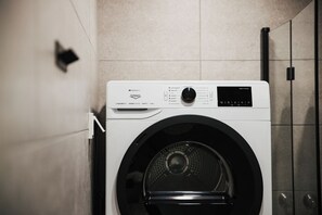 A front-loading washing machine with a control panel and a digital display.