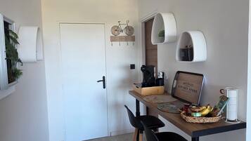 Une cuisine moderne avec une table en bois, des chaises noires et une machine à café.