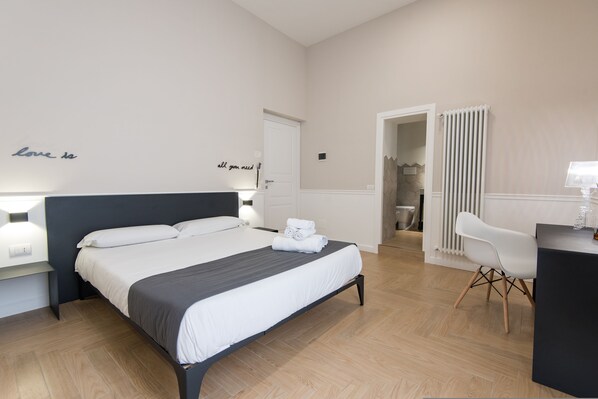 Una camera d'albergo moderna con un letto grande, comodini, una scrivania e una sedia.