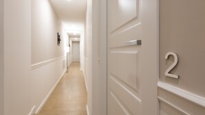 A hallway with a wooden floor and white walls, leading to a room with a door marked with the number 2. - Five Boutique Rooms - Camera 2 (Naples)