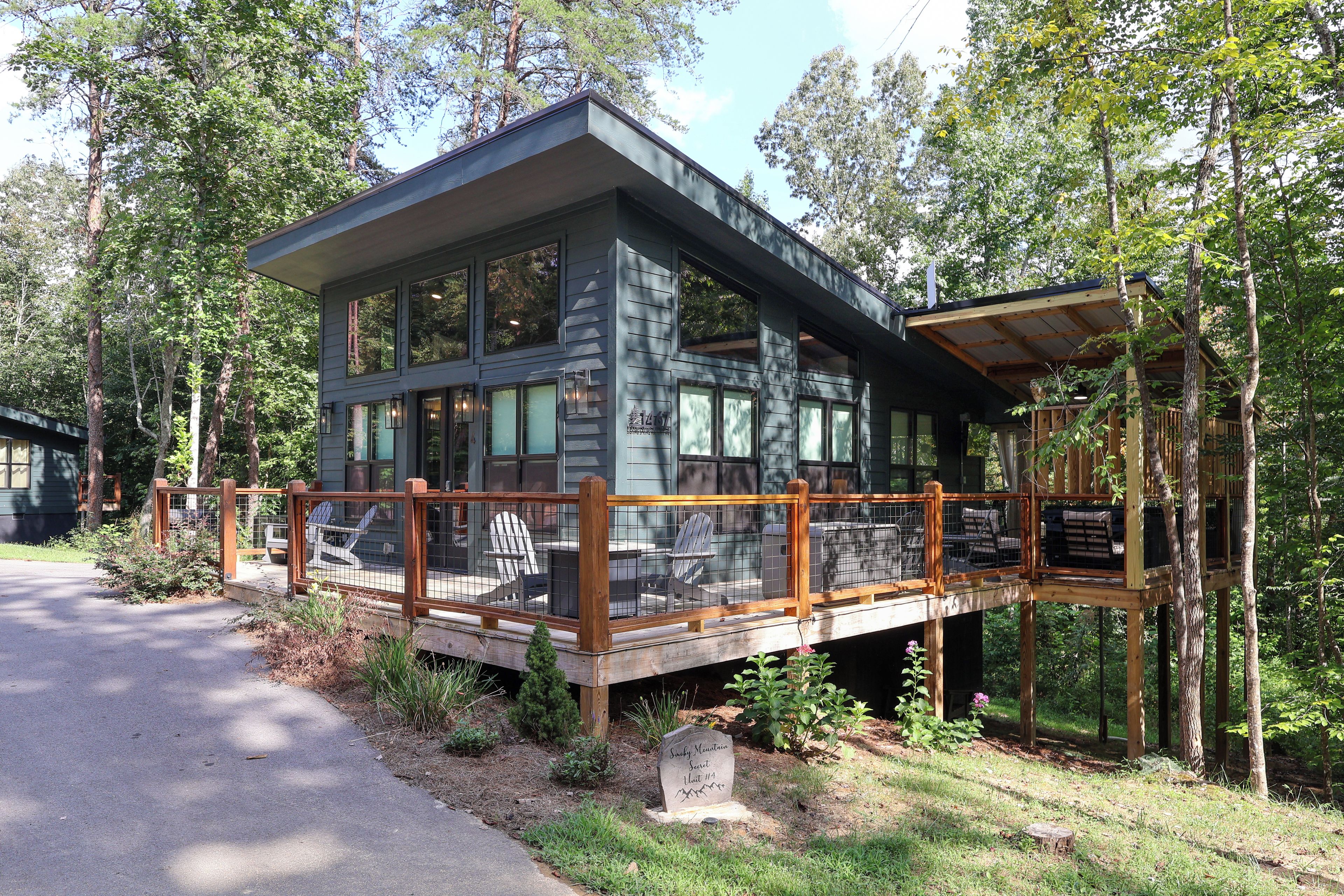 A cabin with a deck, surrounded by trees.