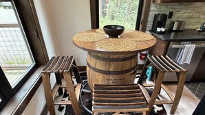 Un tavolo di legno rustico con una ciotola sopra, circondato da sgabelli e un pavimento in pelle di vacca.