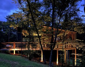 A multi-level wooden cabin with a deck, surrounded by trees. - Gorgeous new 1 bedroom with king bed, outdoor firepit, hot tub, lots of light! (Sevierville)