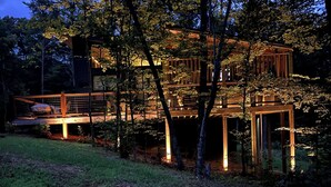 Una baita di legno a più piani con un balcone, immersa tra gli alberi.