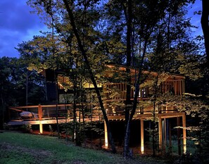A multi-level wooden cabin with a deck, surrounded by trees. - Gorgeous new 1 bedroom with king bed, outdoor firepit, hot tub, lots of light! (Sevierville)