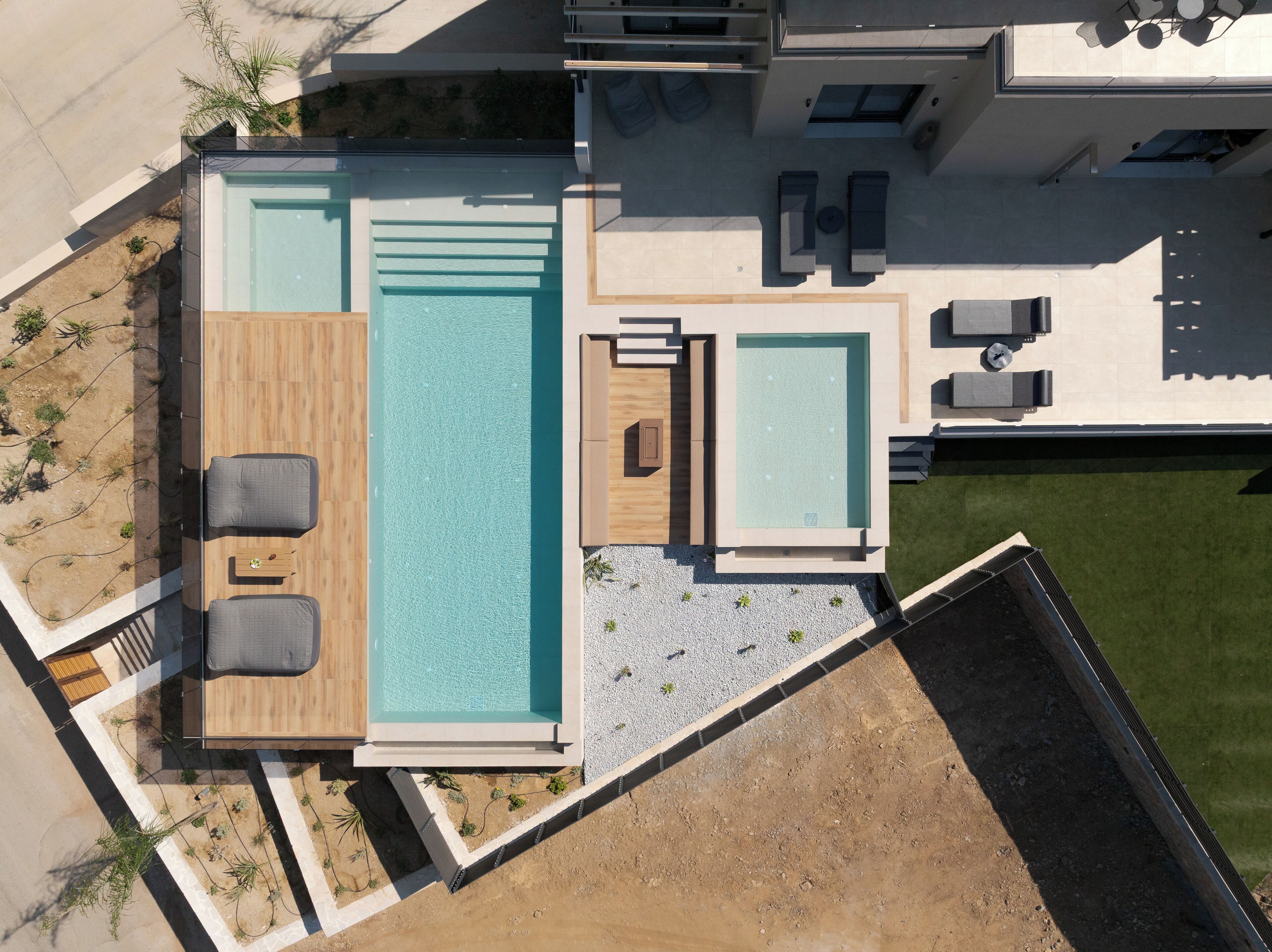 Un espace piscine sur le toit, doté d’une terrasse en bois, de deux piscines distinctes et de coins salon extérieurs.