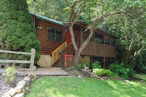 A wooden cabin with a porch and a staircase leading to a deck. - Studio cabin- Firepit, hot tub, near the river, hiking trails, horseshoes! (Sevierville)