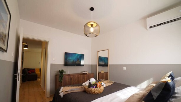 Habitación de hotel con cama, televisor, espejo y aire acondicionado instalado en la pared.