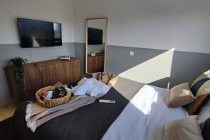 A hotel room with a bed, a television, a mirror, a wooden dresser, and a basket with toiletries. - 4.97 Super Host`s New Boutique & Prime Location (Limassol)