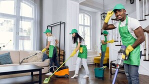 Un grupo de personas limpiando una habitación con sofá, una mesa de centro y una ventana con cortinas.