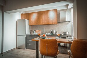 Eine moderne Küche mit Holzschränken, einem Esstisch mit Stühlen und einem Kühlschrank.