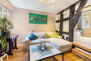 A cozy living room with a sofa, a coffee table, a painting of owls, and a large window.