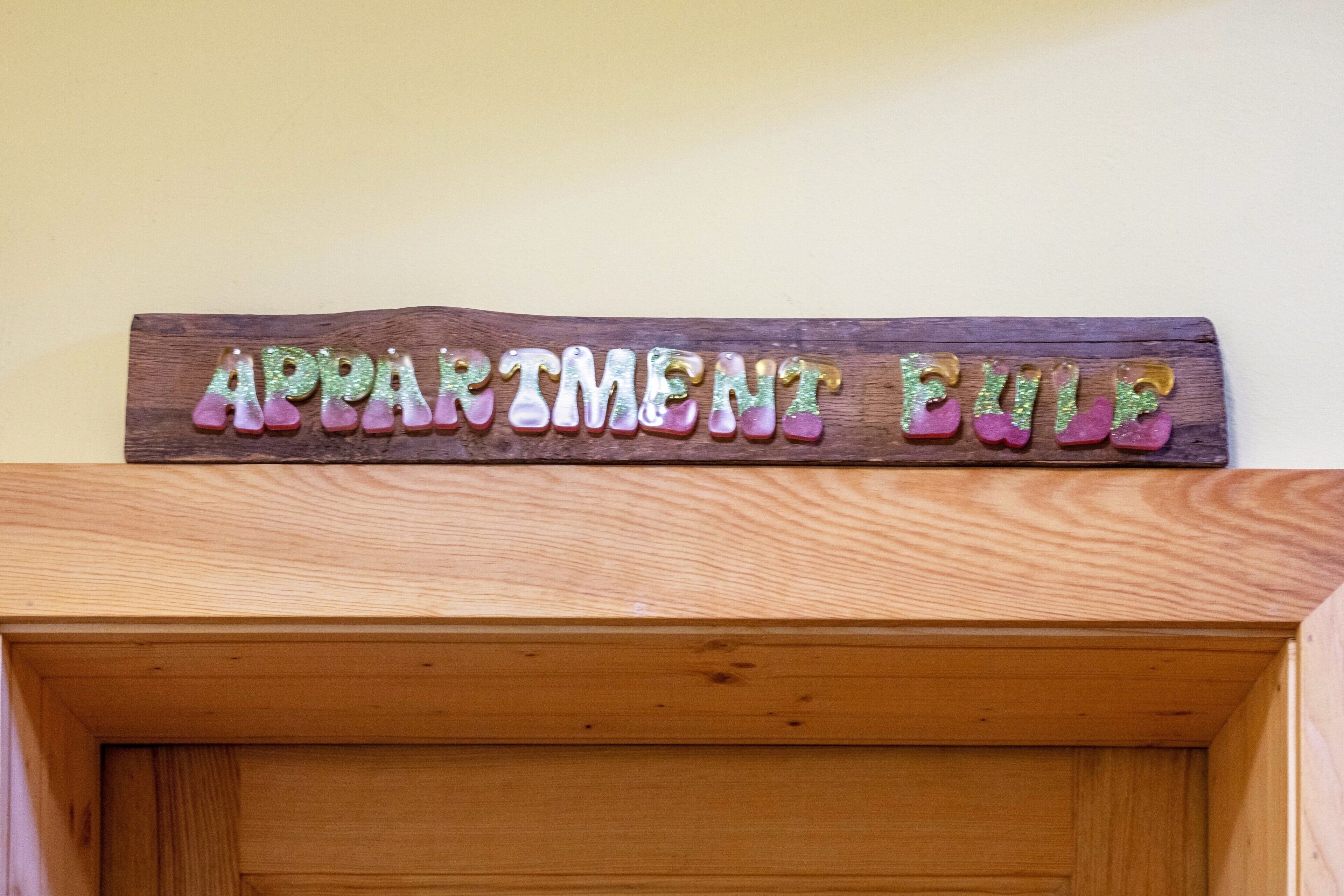 Ein Holzschild mit der Aufschrift 'APARTMENT BUILD', das über einer Holztür angebracht ist.