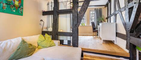 A modern living room with exposed wooden beams, a white sofa with green cushions, and a coffee table with a lamp.