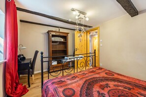 A bedroom with a bed, a desk, a chair, a wardrobe, and a door.