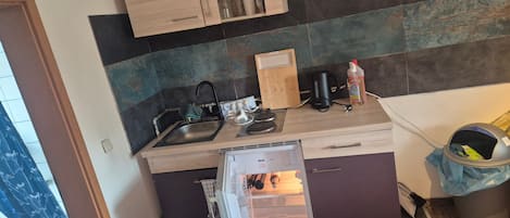 A compact kitchen with a built-in dishwasher, a sink, and a coffee maker.