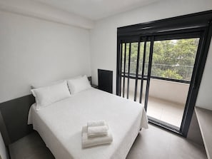 Ein Schlafzimmer mit Bett, Nachttisch und einem Balkon mit Blick.