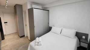A hotel room with a bed, a nightstand, a wardrobe, and a door. - Studio Completo - Aclimação (São Paulo)