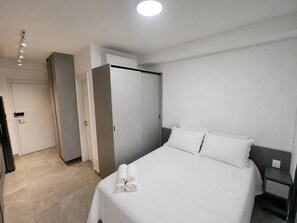 Ein Hotelzimmer mit Bett, Nachttisch, Kleiderschrank und Tür.