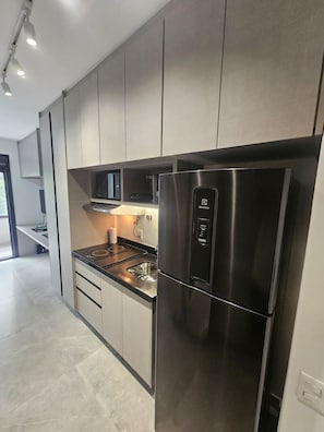 Eine moderne Küche mit Edelstahlgeräten, darunter ein Kühlschrank und eine Mikrowelle, sowie hellem Korpus.