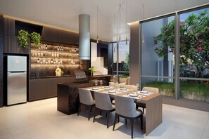 A modern kitchen with a built-in island, a refrigerator, and a dining area with chairs and a table set for two. - Studio Completo - Aclimação (São Paulo)