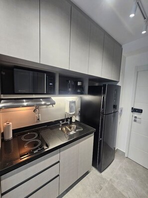 A modern kitchen with stainless steel appliances, a double sink, and grey cabinetry. - Studio Completo - Aclimação (São Paulo)
