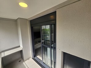 Ein Balkon mit Glastür, die zu einem Außenbereich führt, einer Deckenleuchte und einer strukturierten Wand.