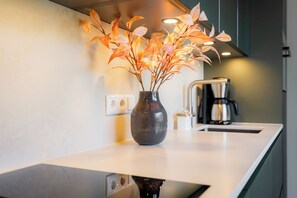 A kitchen with a white countertop, a dark ceramic vase with a plant, and a coffee maker. - Wind Force 7 - Sea State. Sauna. Patio. Dog-Friendly (Grömitz)